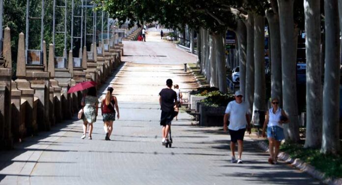 Vianants caminant per l'ombra a Lleida sota una intensa calor.