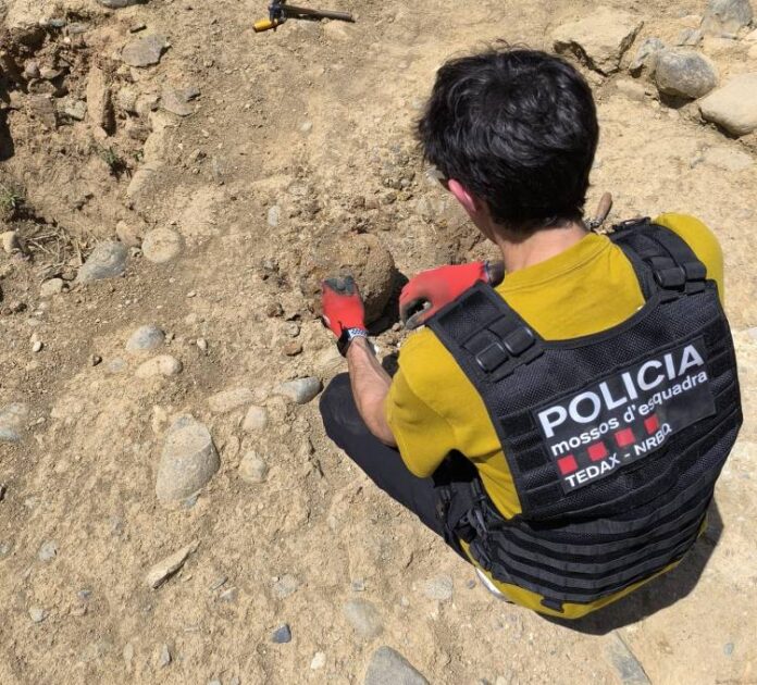 Un mosso d'esquadra dels TEDAX a tocar del projectil trobat al jaciment del pati de les Monges de la Seu d'Urgell.