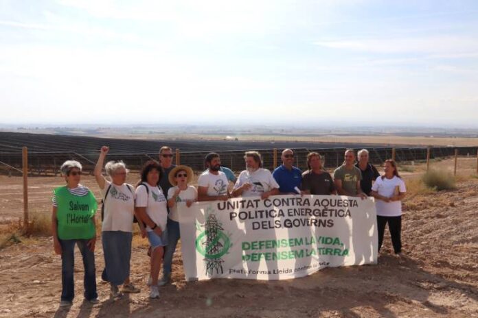 Plataformes, organitzacions ecologistes i sindicats agraris, amb una pancarta al davant del megaparc solar d'Alcarràs